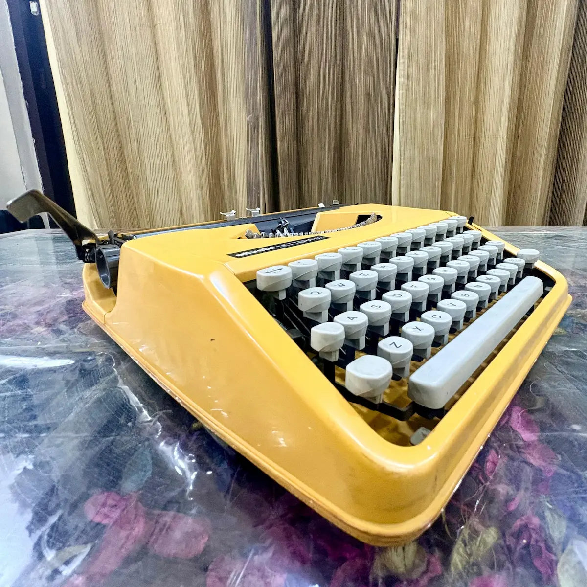 Angled overhead photograph of yellow Olivetti Lettera 82 manual typewriter with white keys at RR Typewriter Mart