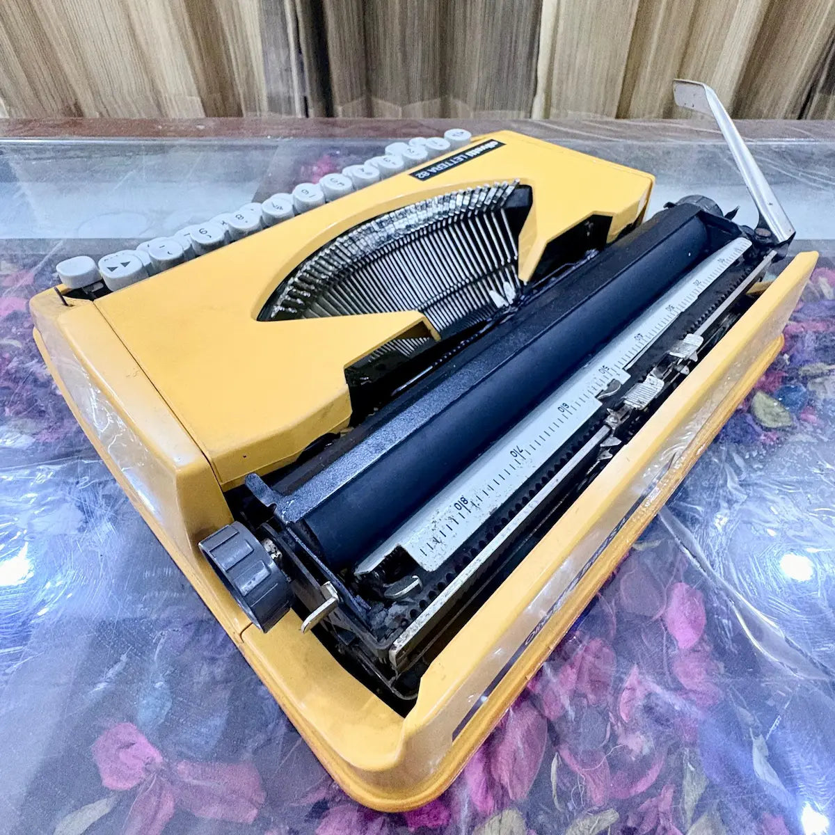 Angled rear view of Olivetti Lettera 82 yellow portable manual typewriter, showing black platen, metal carriage and typebars, RR Typewriter Mart