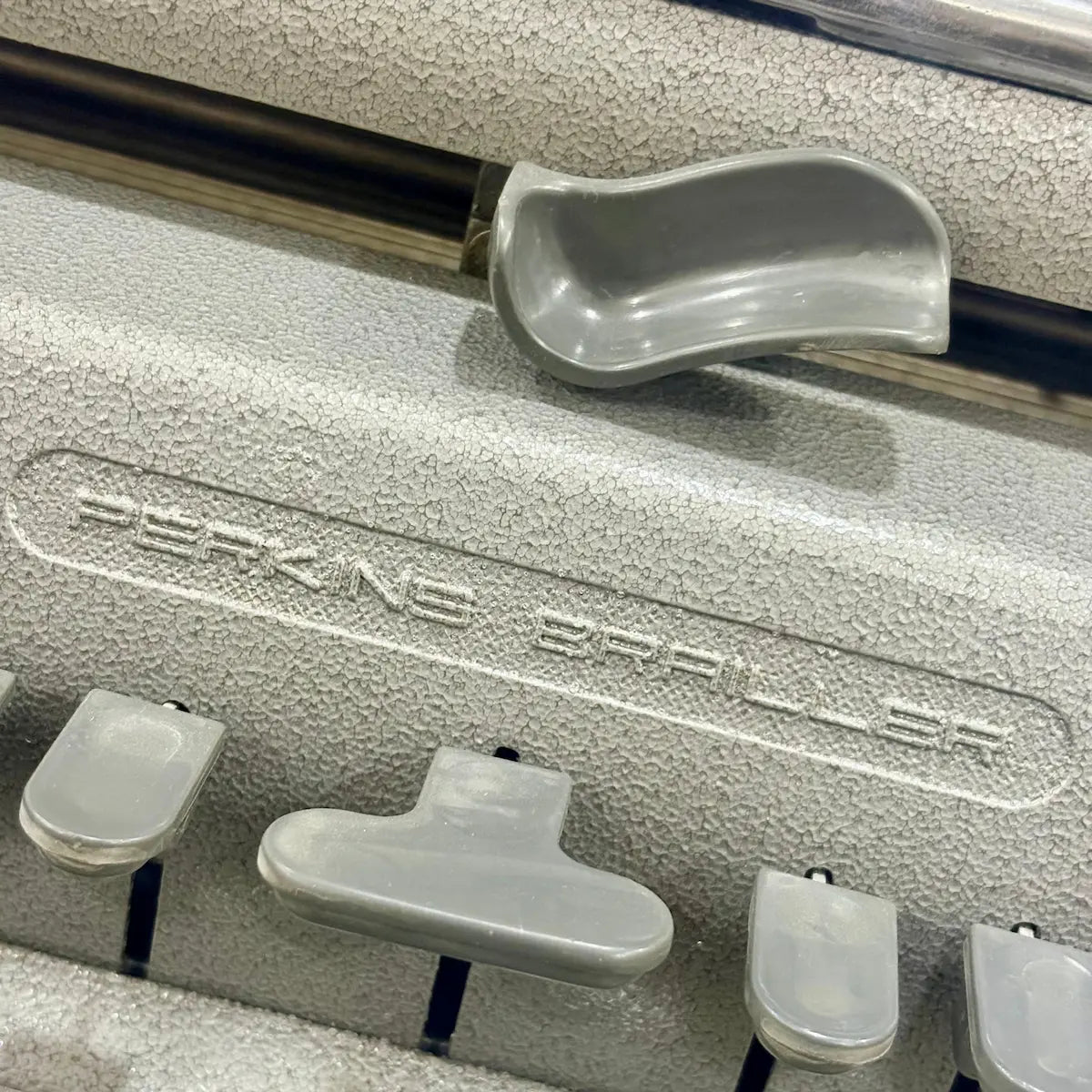 Side angle of the Perkins Braille Typewriter showing textured factory paint, metal body and paper feed at RR Typewriter Mart India.