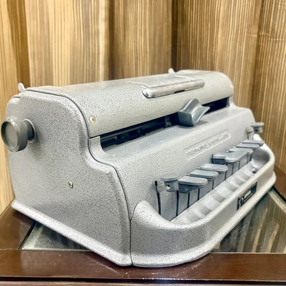 Side profile of the Perkins Brailler showing the platen knob and original grey factory finish at RR Typewriter Mart in India today.
