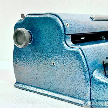 Close-up of a blue Perkins Braille Typewriter showing its textured metal body and carriage knob, ideal for Braille typewriter servicing at RR Typewriter Mart