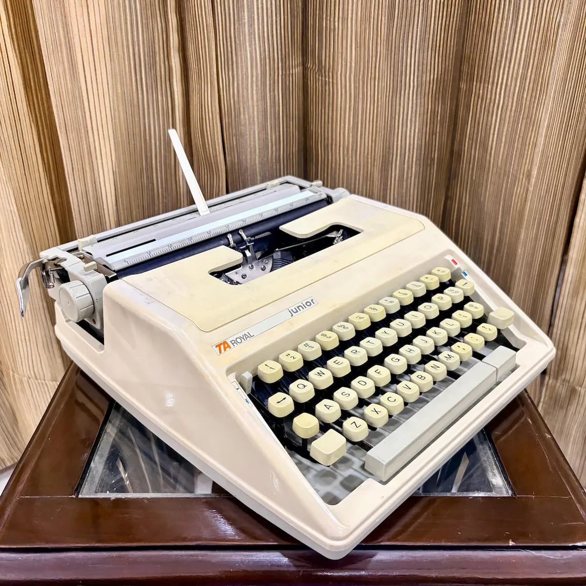 Royal Junior portable typewriter three-quarter view showing cream body, keyboard and carriage, from RR Typewriter Mart.