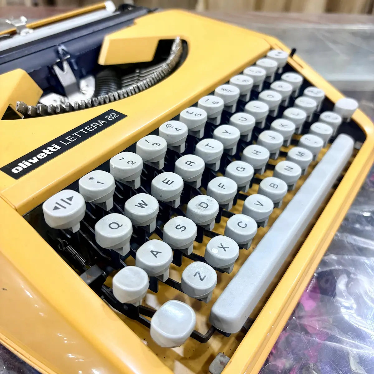 Close-up of Olivetti Lettera 82 model badge on yellow body, identifying this portable typewriter at RR Typewriter Mart