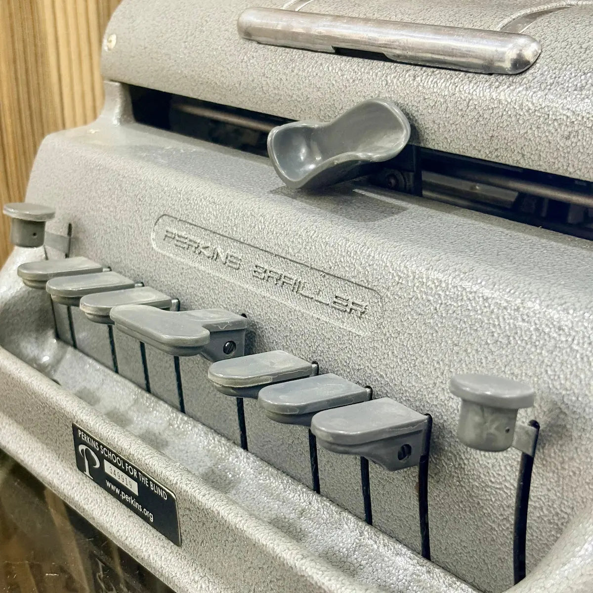 Front detail of the mint grey Perkins Brailler showing six primary keys and sturdy metal body at RR Typewriter Mart for Braille users.