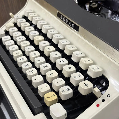 Kovac portable manual typewriter featuring a charcoal grey panel, ivory body and cream keyboard in untouched condition | RR Typewriter Mart