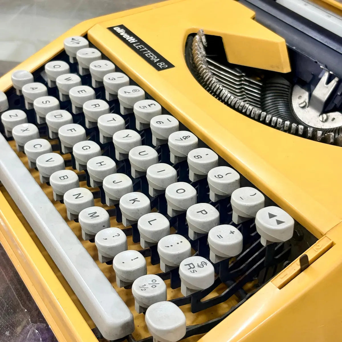 Rear side view of yellow Olivetti Lettera 82 typewriter with carriage assembly at RR Typewriter Mart