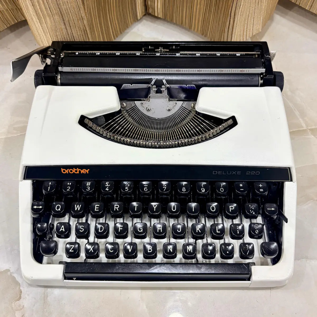 Brother Deluxe 220 Pearl White typewriter showing cream-white body, black keys and traditional mechanical typing mechanism in India