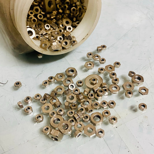Assorted manual typewriter nuts spilled from container for repair work, typewriter spare parts by RR Typewriter Mart
