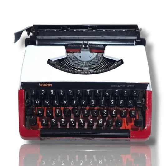 Brother Deluxe 220 Swiss portable typewriter in red and white, front view with QWERTY keyboard and manual carriage