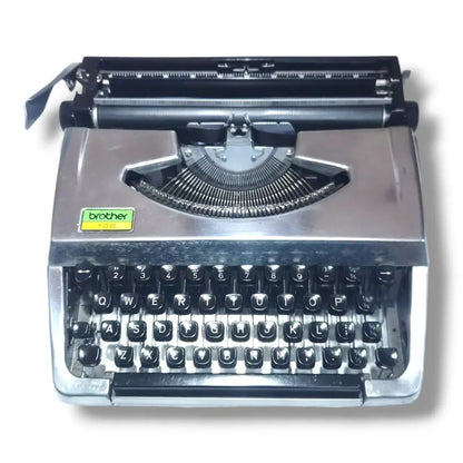 Front view of Brother 100 Deluxe chrome typewriter, English manual typing machine with black keys and plated body