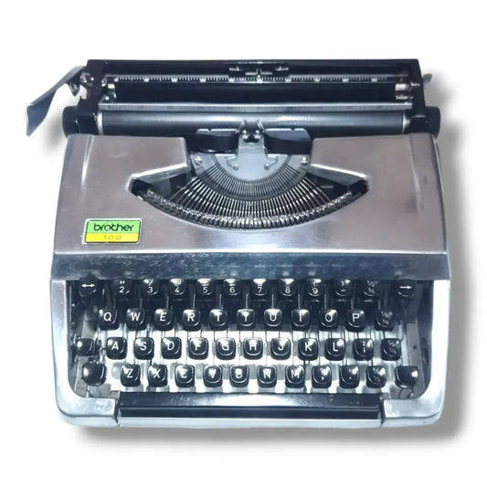 Front view of Brother 100 Deluxe chrome typewriter, English manual typing machine with black keys and plated body
