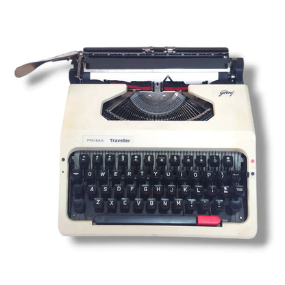 Godrej Prima Traveller portable typewriter front view with beige body, black English keyboard and visible typebars