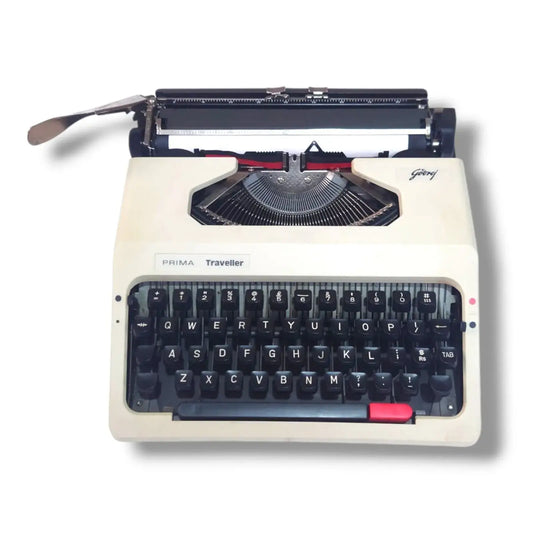 Godrej Prima Traveller portable typewriter front view with beige body, black English keyboard and visible typebars