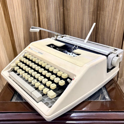 Royal Junior manual typewriter three-quarter view showing cream body, keyboard and carriage, from RR Typewriter Mart.