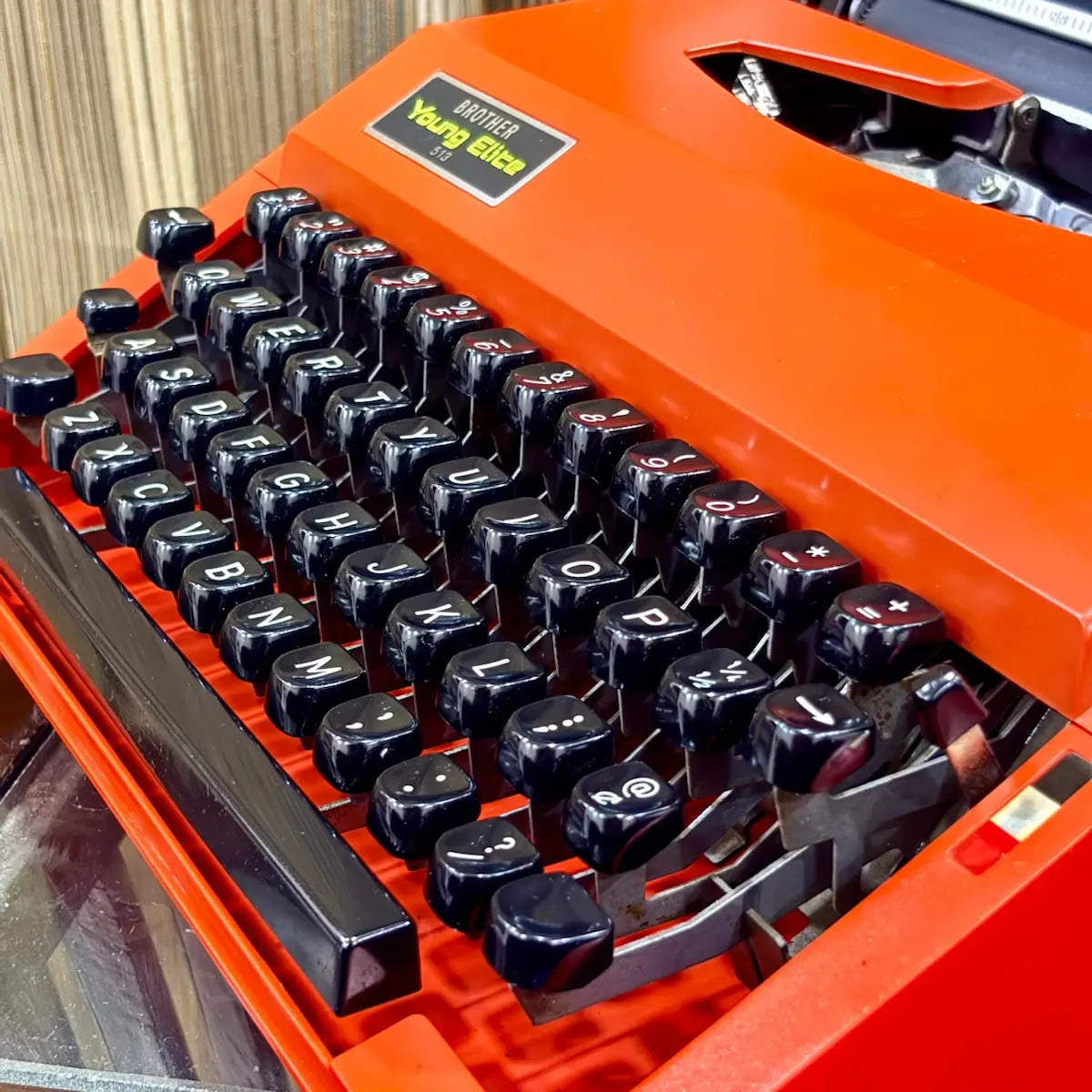 Scarlet red Brother Young Elite 513 portable typewriter, angled view of body panels and black keys for vintage collectors | RR Typewriter Mart