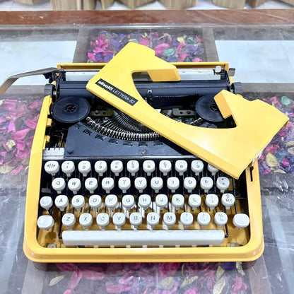 Side angle of yellow Olivetti Lettera 82 portable typewriter showing design and white keys at RR Typewriter Mart