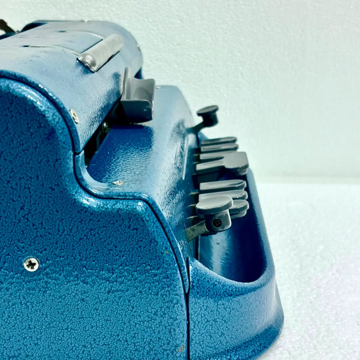 Close-up of blue Perkins Braille Typewriter keys and textured metal body, a braille typing machine from RR Typewriter Mart.