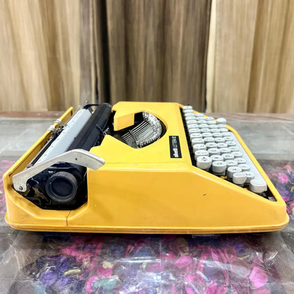 Yellow Olivetti Lettera 82 portable manual typewriter with white keys, side profile and exposed carriage, photographed at RR Typewriter Mart