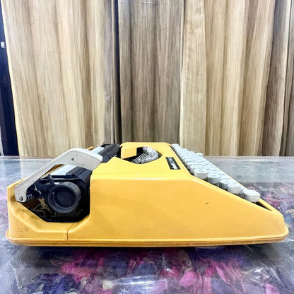 Yellow Olivetti Lettera 82 portable manual typewriter showing side profile, white keyboard and black carriage mechanism, RR Typewriter Mart
