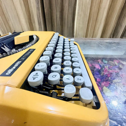 Close-up of Olivetti Lettera 82 yellow manual typewriter showing white QWERTY keys and model badge, RR Typewriter Mart
