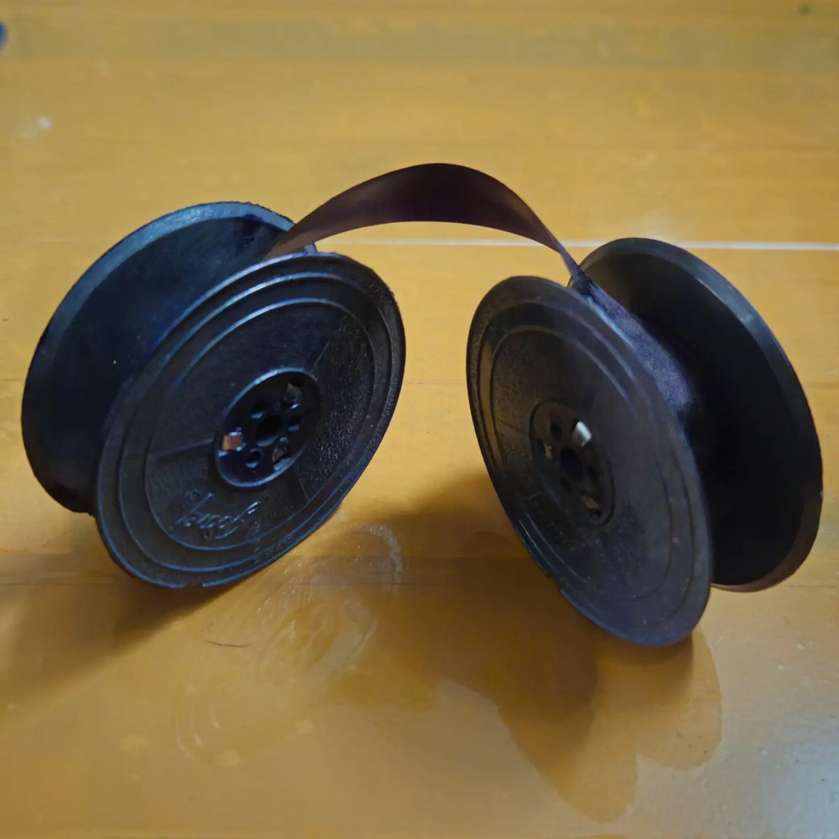 Purple typewriter ribbon roll stretched between spools, ribbon for typing machine from ribbon roll store