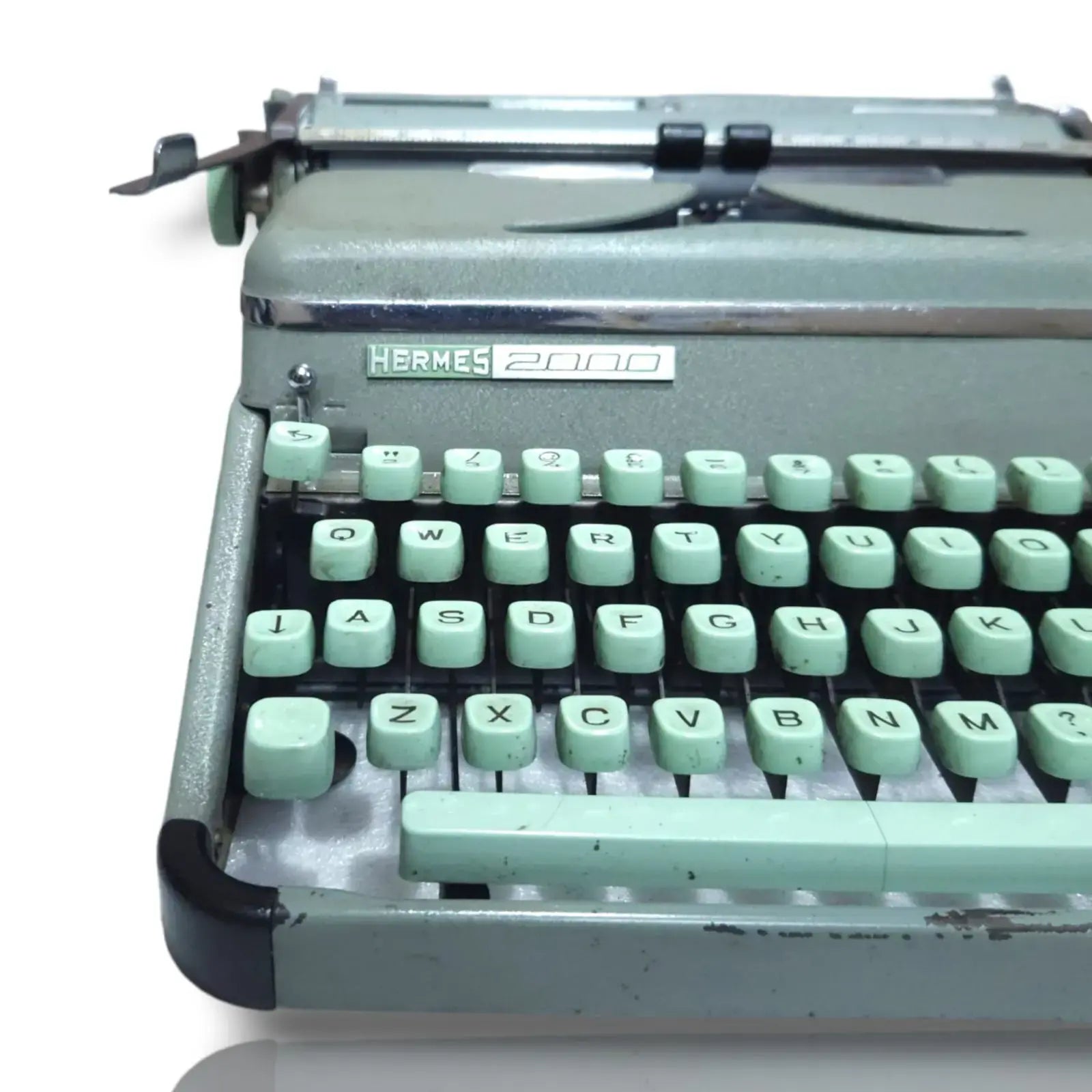 Vintage Hermes 2000 typewriter with green keys on a white background