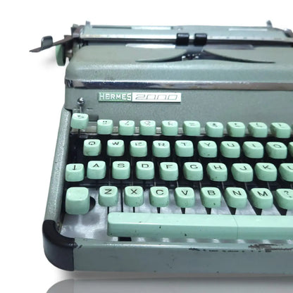 Vintage Hermes 2000 typewriter with green keys on a white background