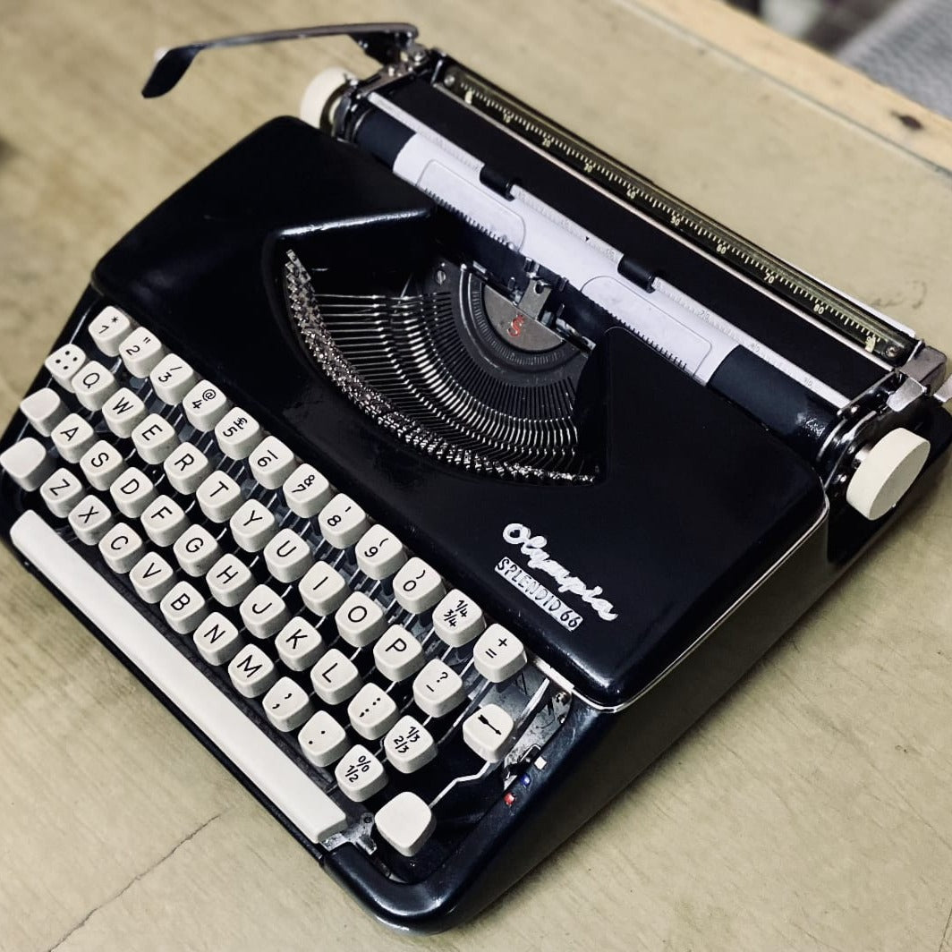 Angled Olympia Splendid 66 typewriter, black German portable typing machine with cream English QWERTY keyboard