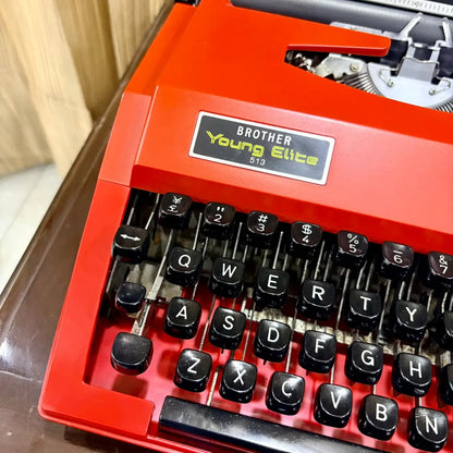 Brother Young Elite 513 red manual typewriter close-up, displaying black QWERTY keys and distinctive original red finish | RR Typewriter Mart