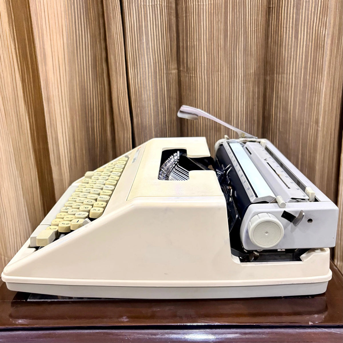 Royal Junior portable typing machine side view showing cream housing and carriage mechanism, from RR Typewriter Mart.