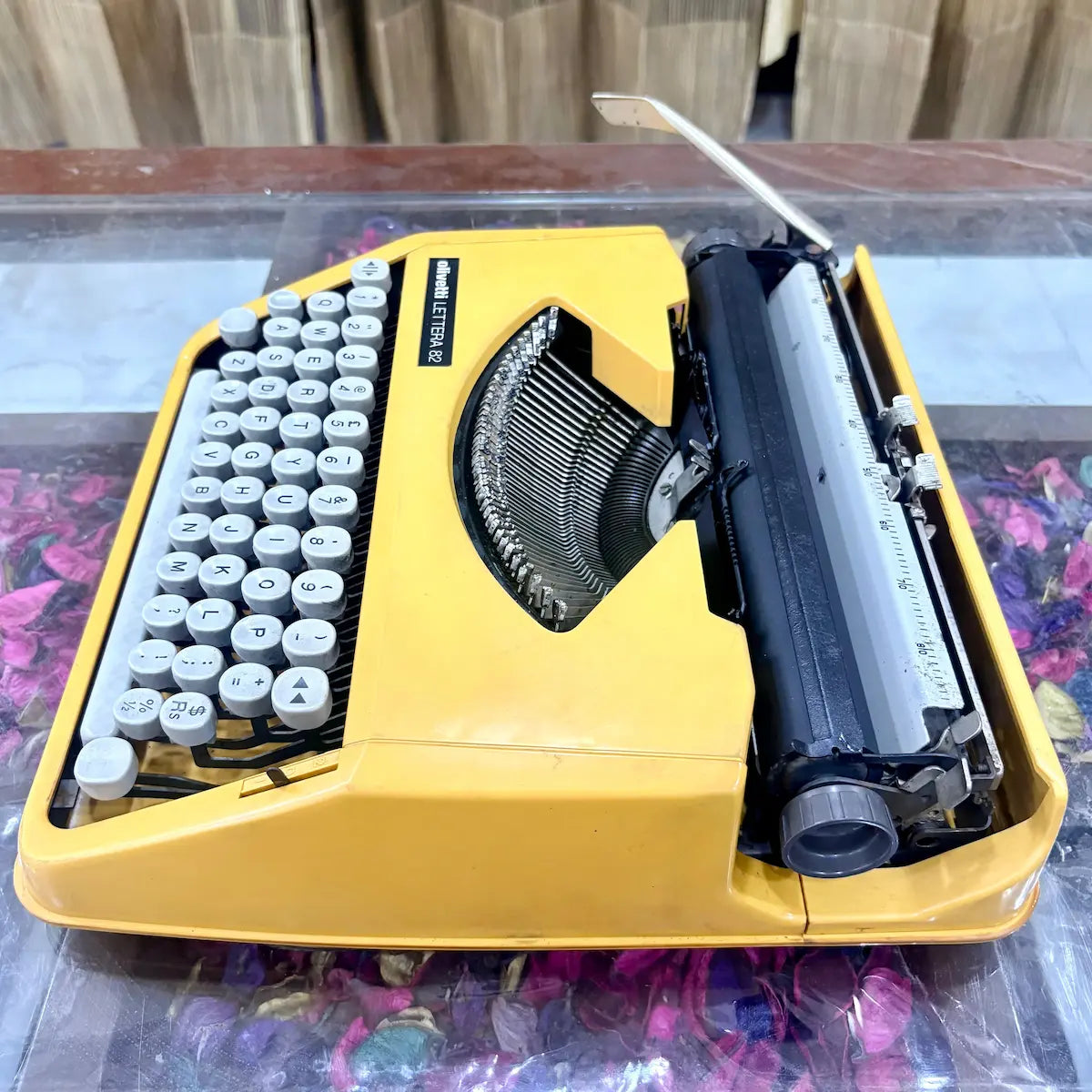Top-down angled view of Olivetti Lettera 82 yellow portable typewriter, showing English QWERTY keyboard, typebars and carriage, RR Typewriter Mart