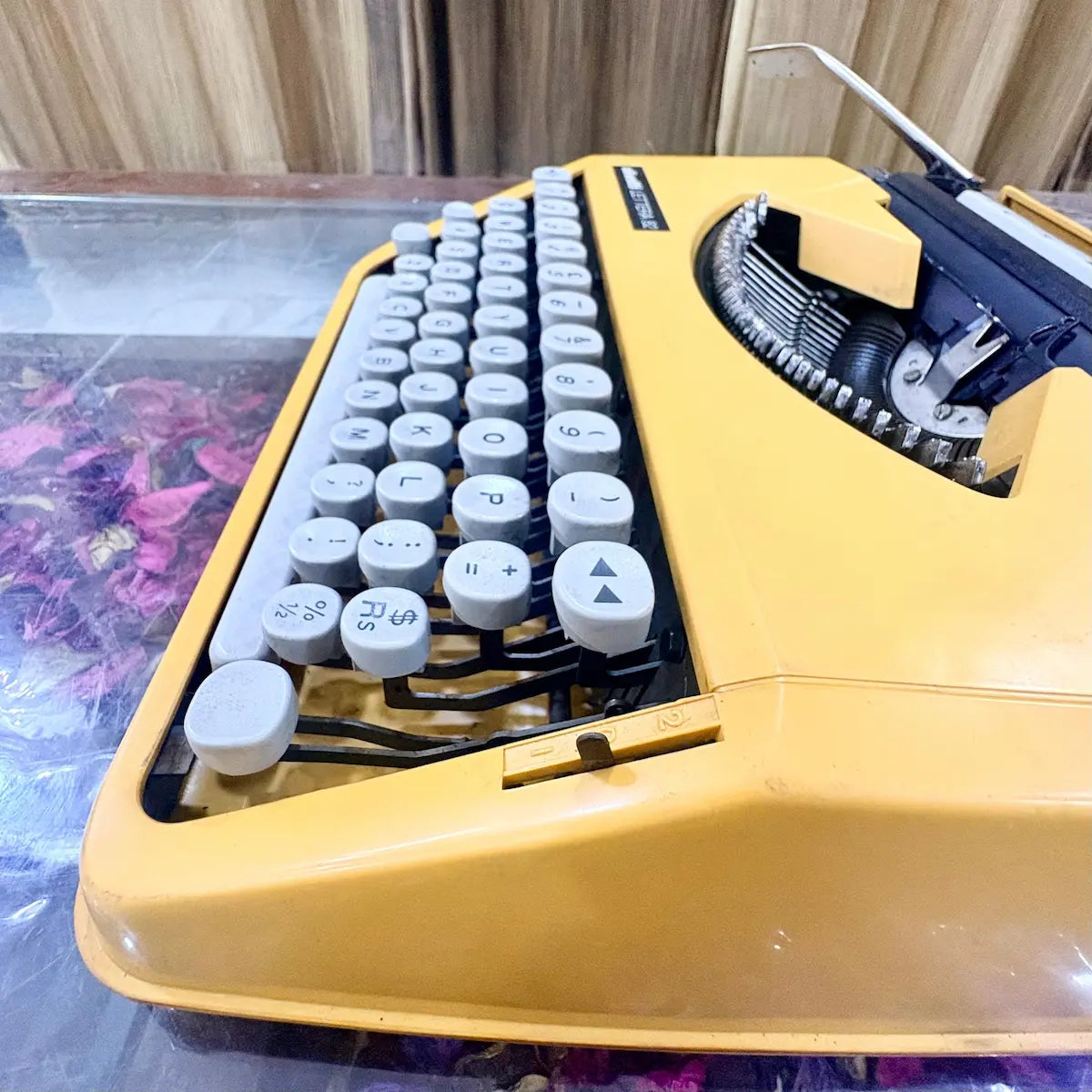 Close-up of Olivetti Lettera 82 yellow portable manual typewriter, showing white QWERTY keys, exposed typebars and yellow casing, RR Typewriter Mart