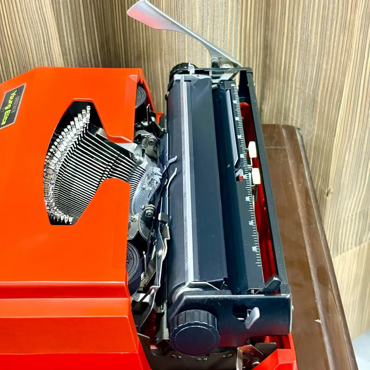 Brother Young Elite 513 scarlet red typewriter side view, highlighting the portable body, keyboard profile and vintage design | RR Typewriter Mart