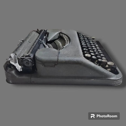 Side view of Hermes Baby Rocket portable typewriter showing compact metal body, carriage and manual keyboard