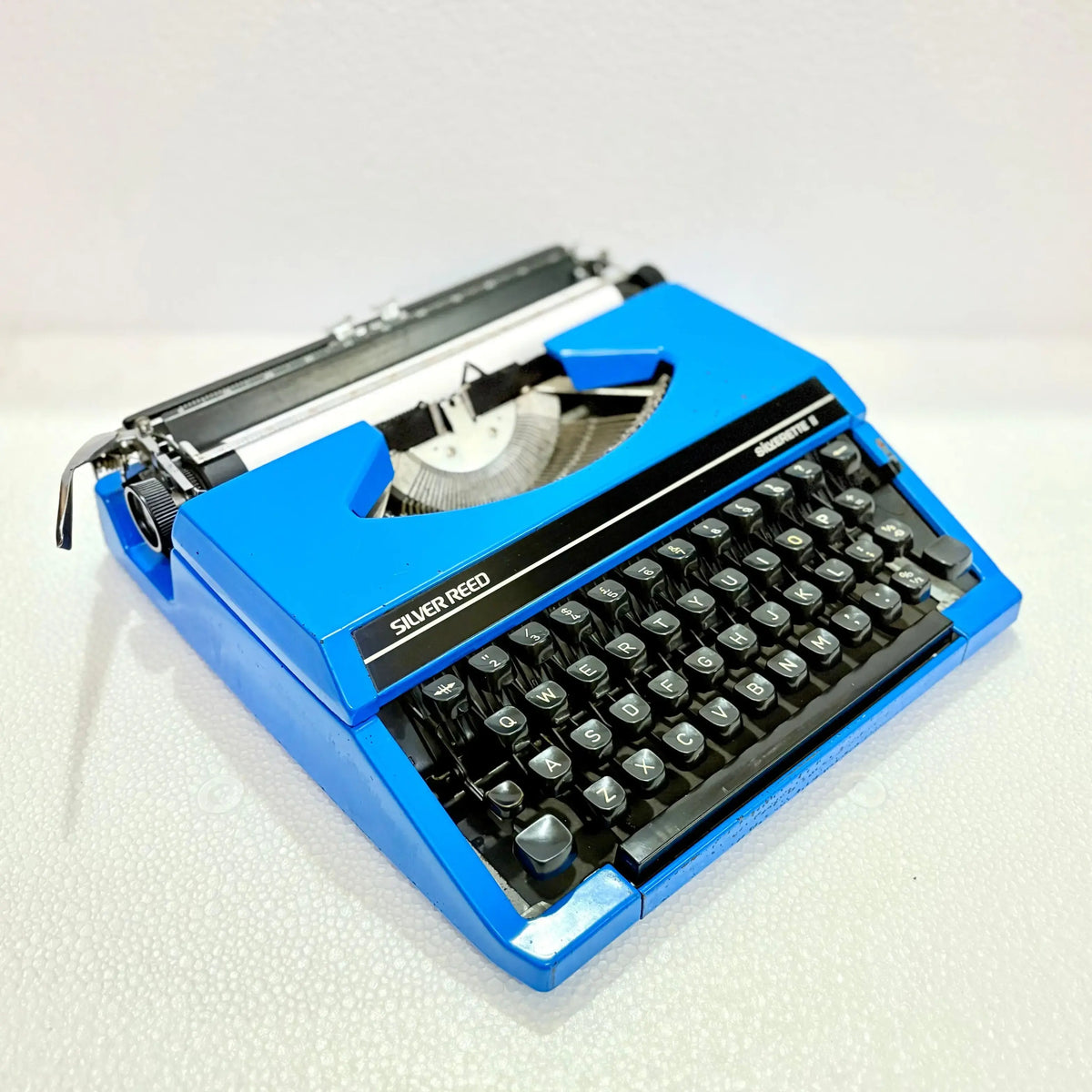 Angled view of deep blue Silver Reed portable Japanese typewriter showing keys, manual typewriter built for writers