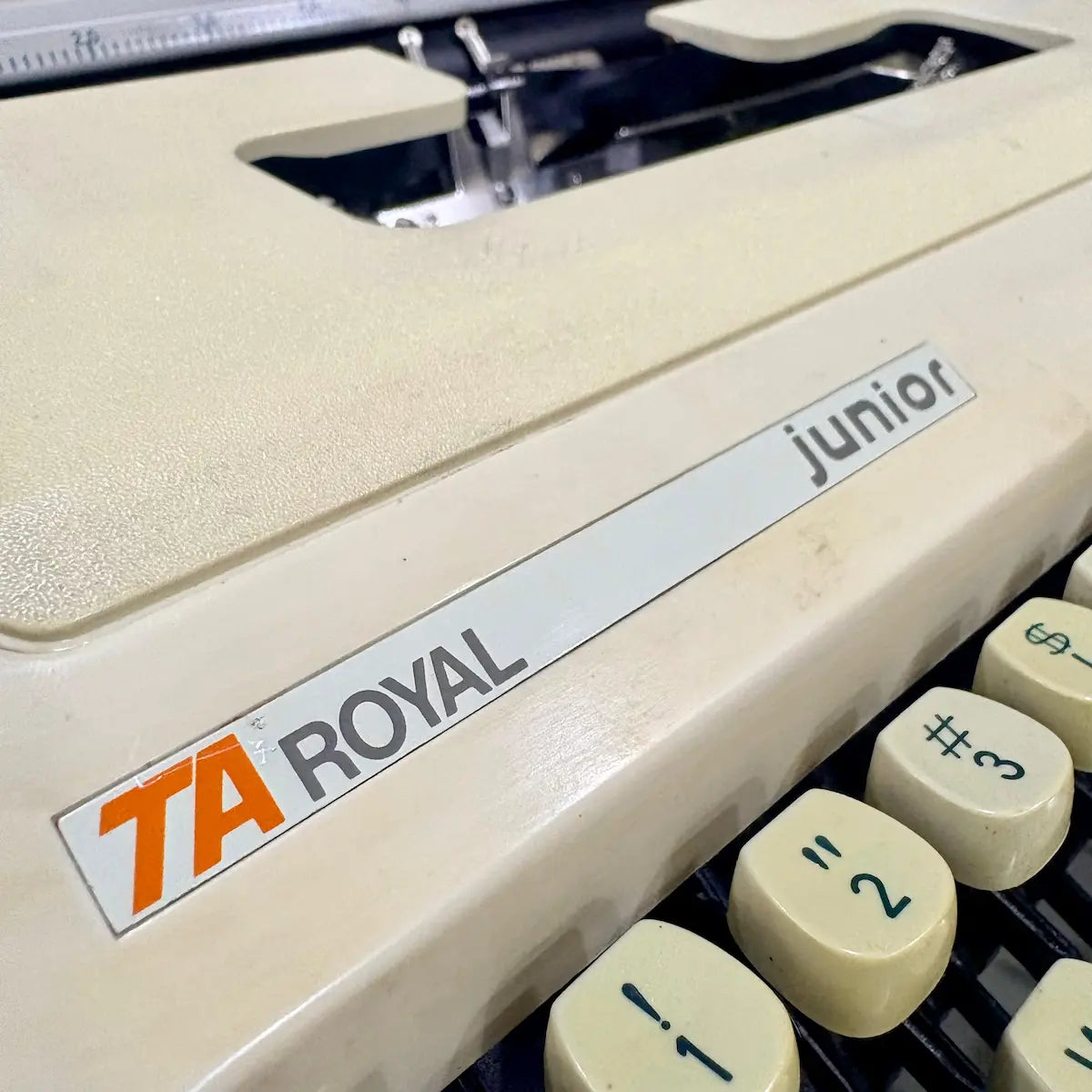 Royal Junior semi portable typewriter close-up showing model branding and cream vintage body, from RR Typewriter Mart.
