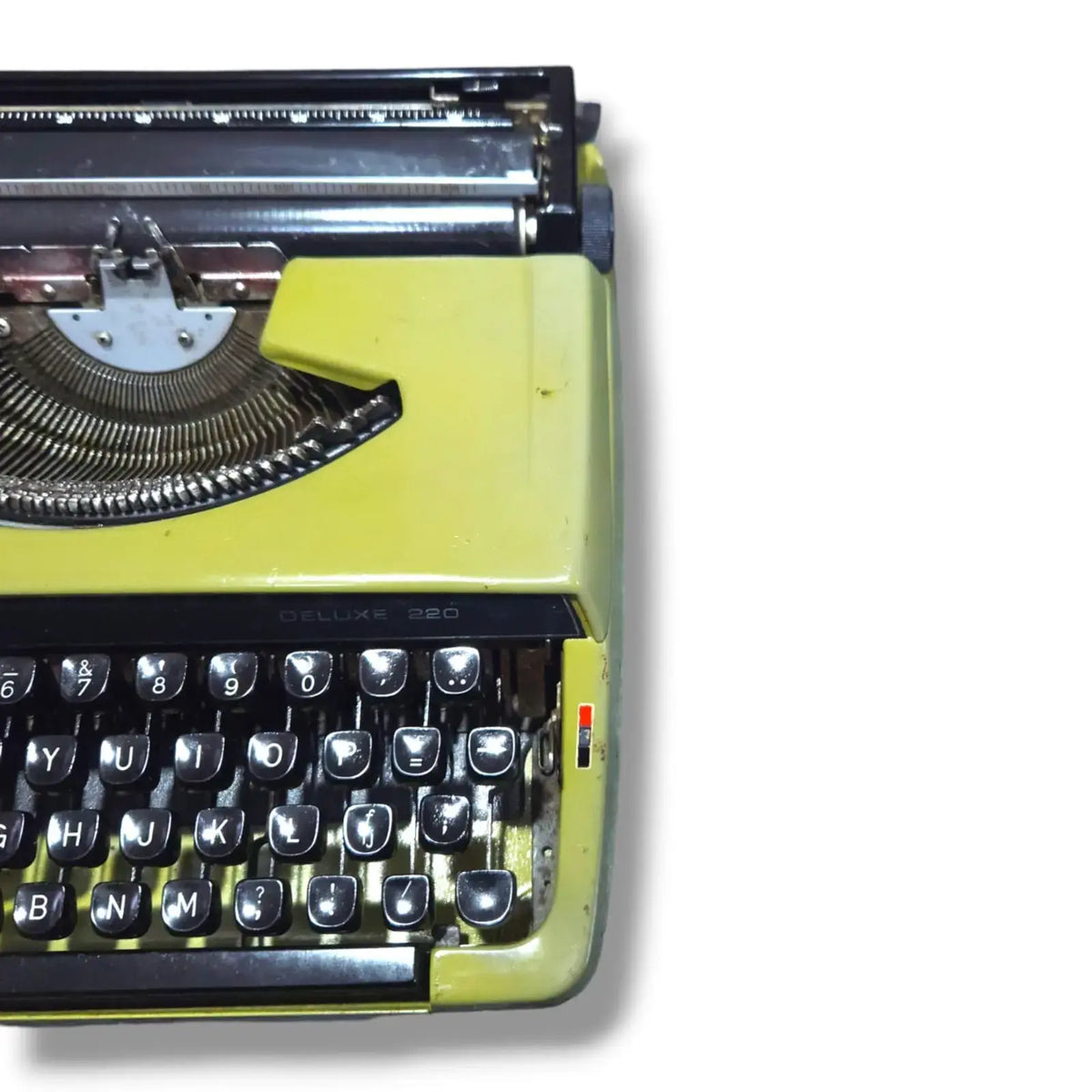 Detail view of Brother Deluxe 220 olive green typewriter, vintage manual typing machine with black keys and carriage