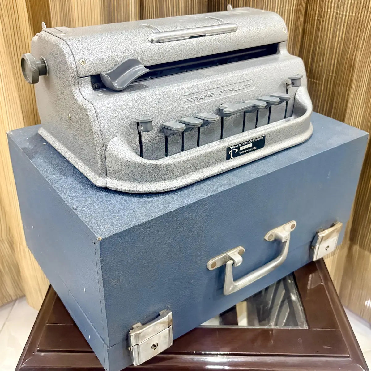 American assembled Perkins Brailler beside its rare blue wooden case, available from RR Typewriter Mart for Braille users in India.