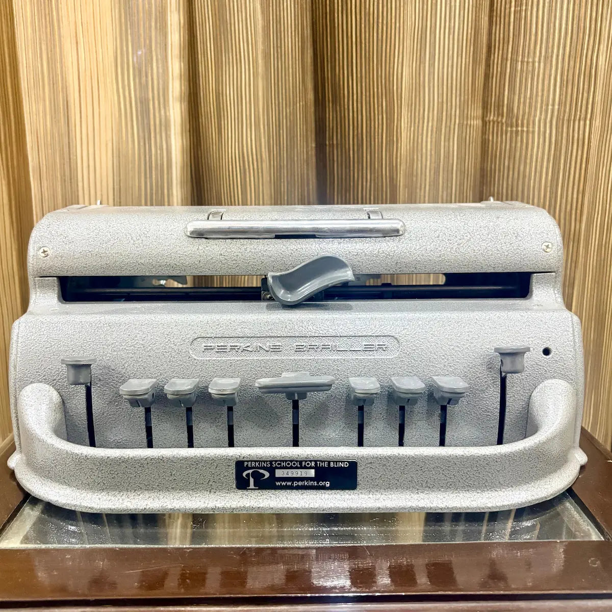 Mint grey Perkins Braille writing machine photographed straight on, with its keys and textured body visible at RR Typewriter Mart.